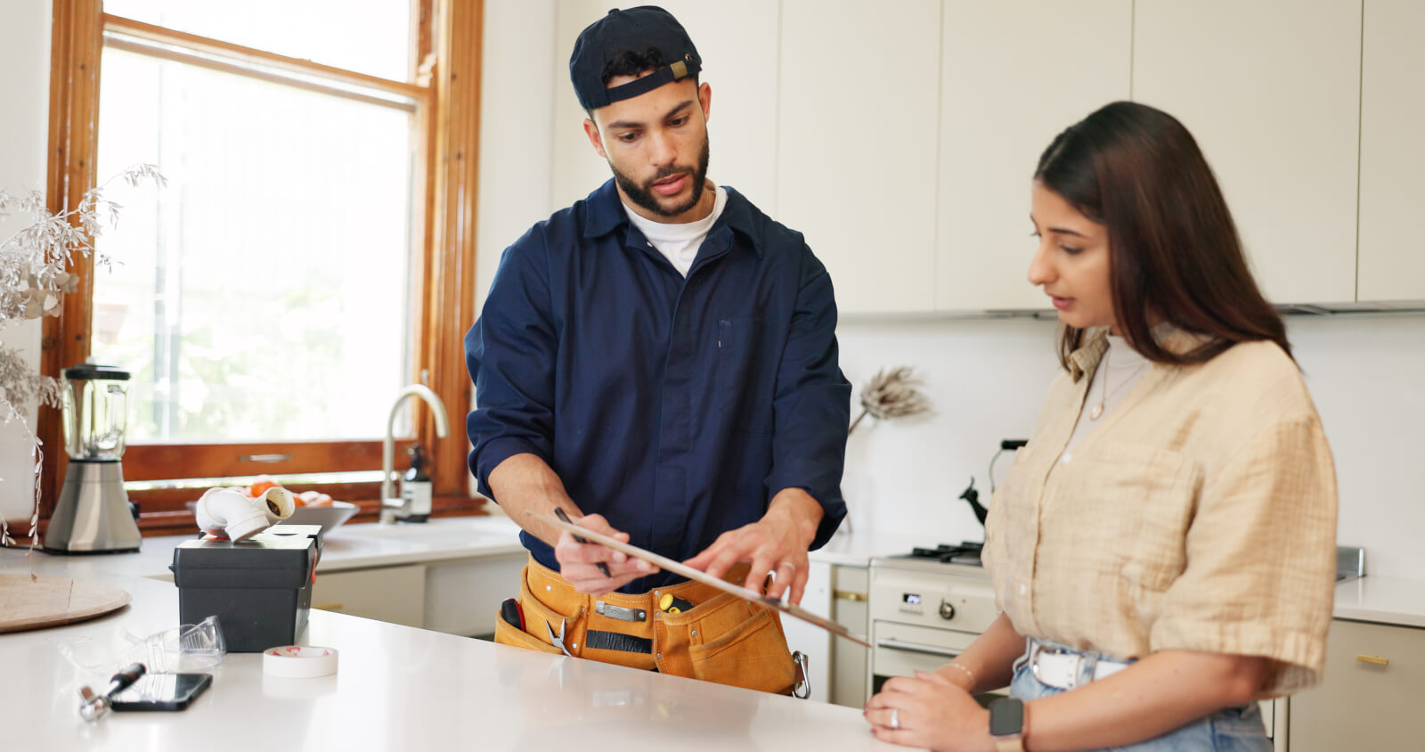 A contractor and a homeowner going over plans at a kitchen counter
